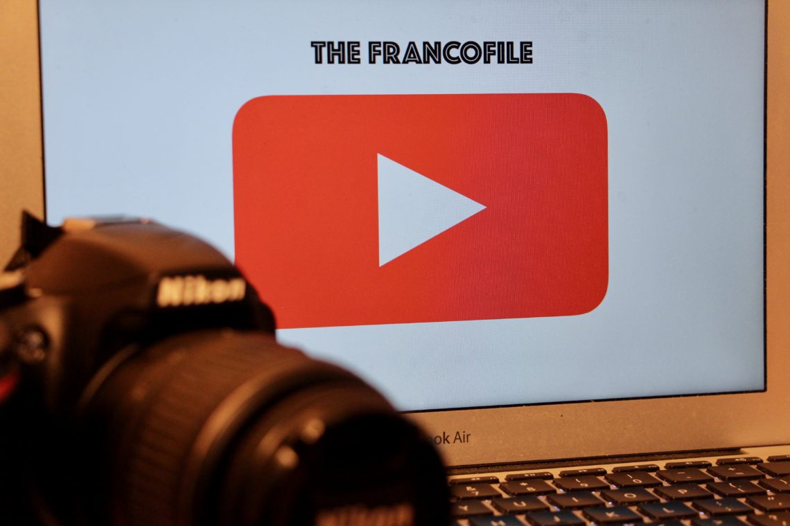 A Nikon camera in front of a computer screen showing the YouTube play button and "The Francofile."