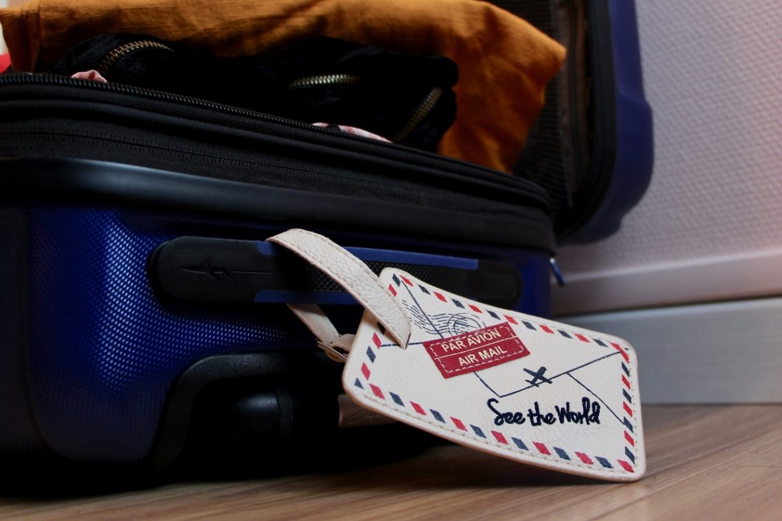 Suitcase filled with clothes with luggage tag attached.
