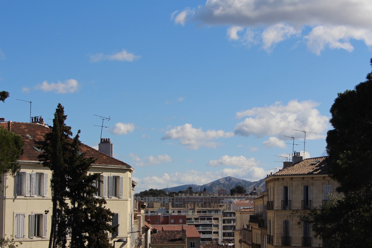 A view of a mountain and rooftops on a sunny day in Marseille.