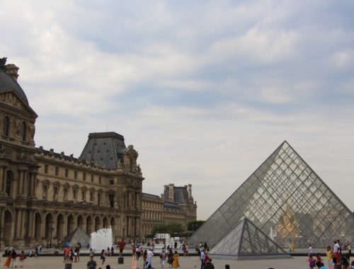 A view of the Louvre Pyramids with people in the area.