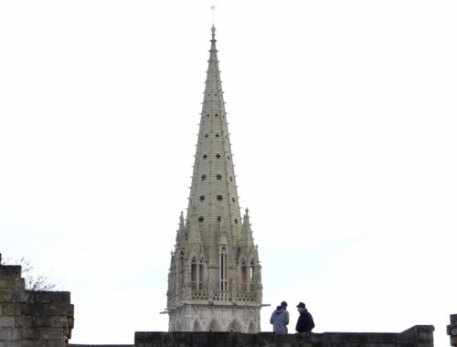 Two people sitting on a ledge facing a large tower.