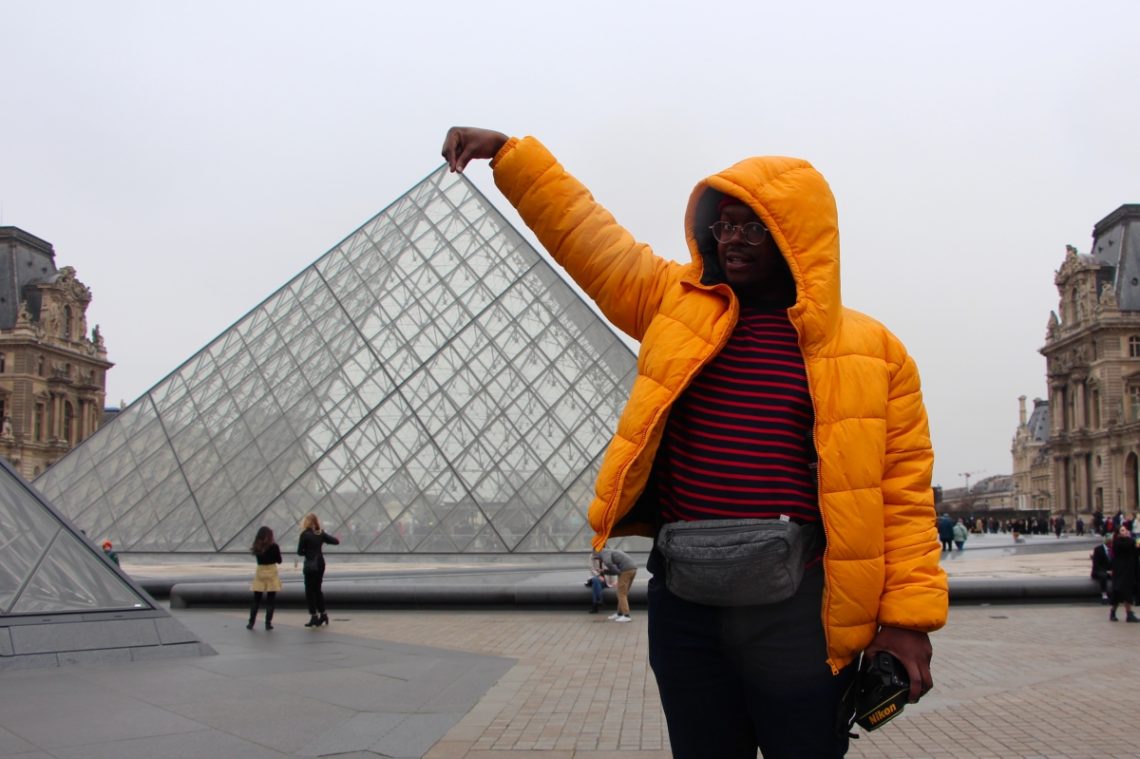 Jalen striking a tourist pose at the Louvre's glass pyramids.