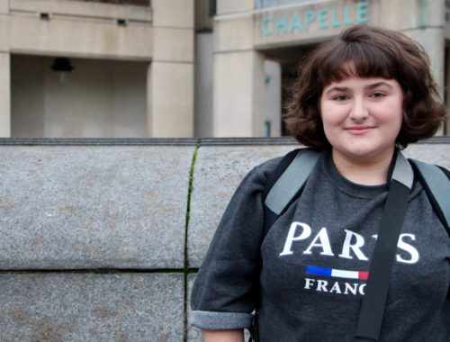Maria smiling wearing a sweatshirt that says Paris, France.