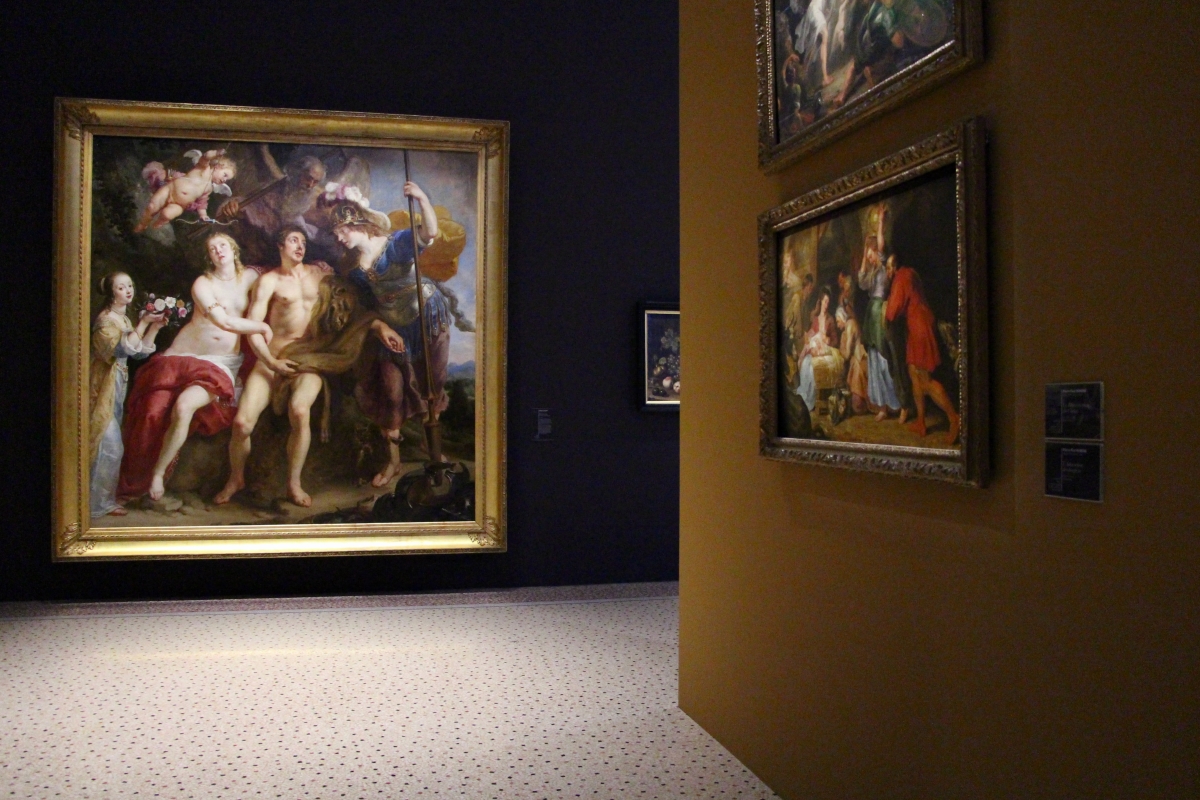 A dark hallway in a museum with three paintings.