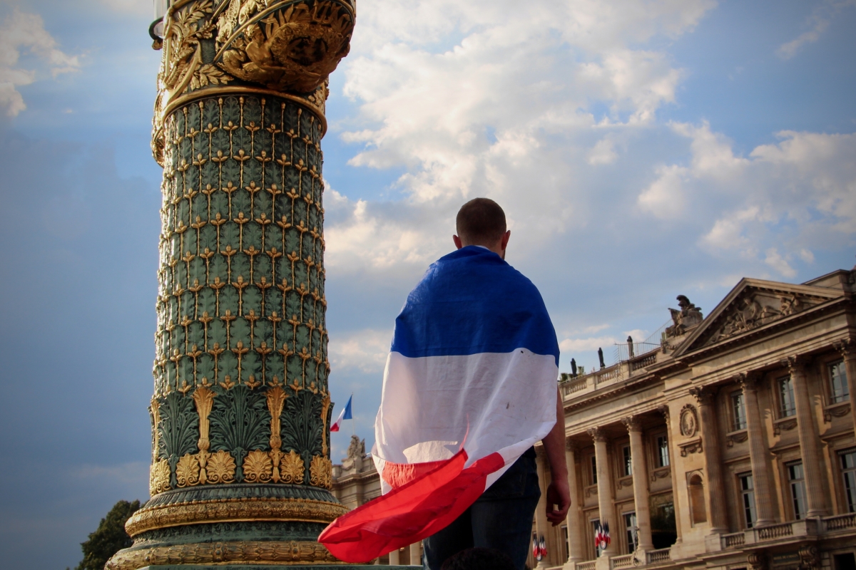 A man with the French flag draped over his shoulders.