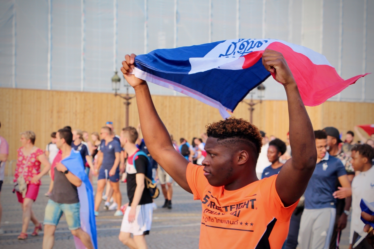 A man waving the French flag among a crowd.