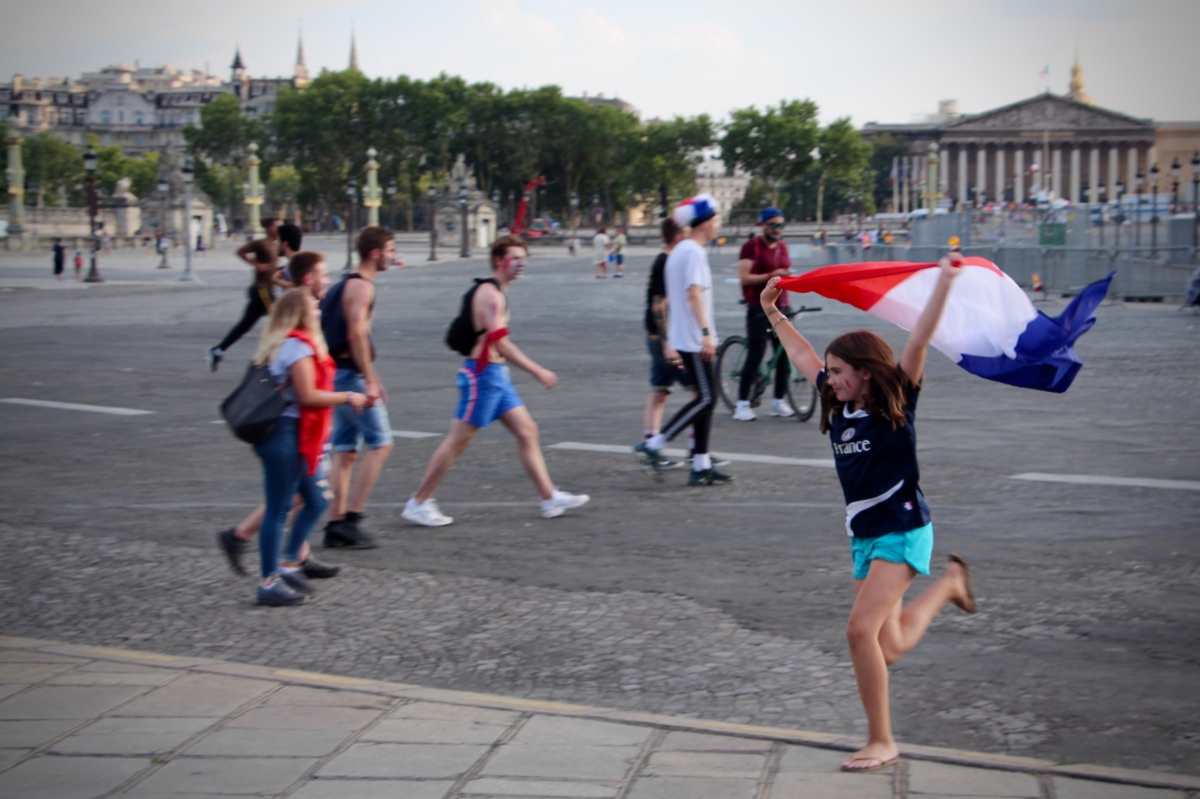 A girl running with a French flag in her arms.