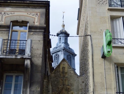 A blue tower peaking through two buildings in Reims, France.