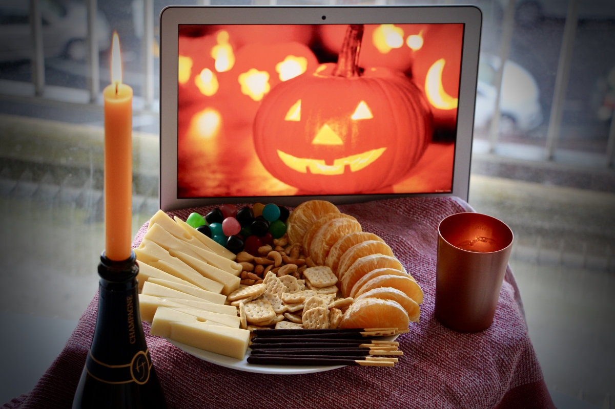 A plate full of snacks is in the foreground, surrounded by two candles, with a pumpkin photo in the background.