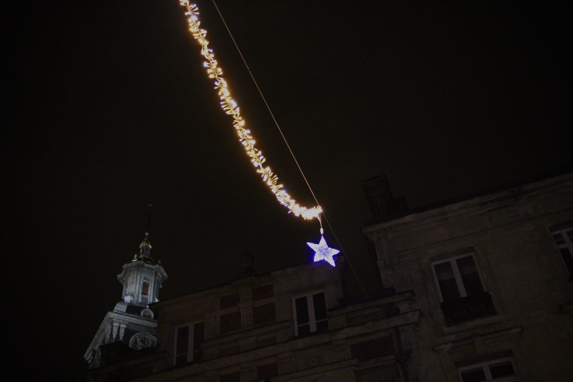 A string of yellow and blue holiday lights across two buildings in Reims.