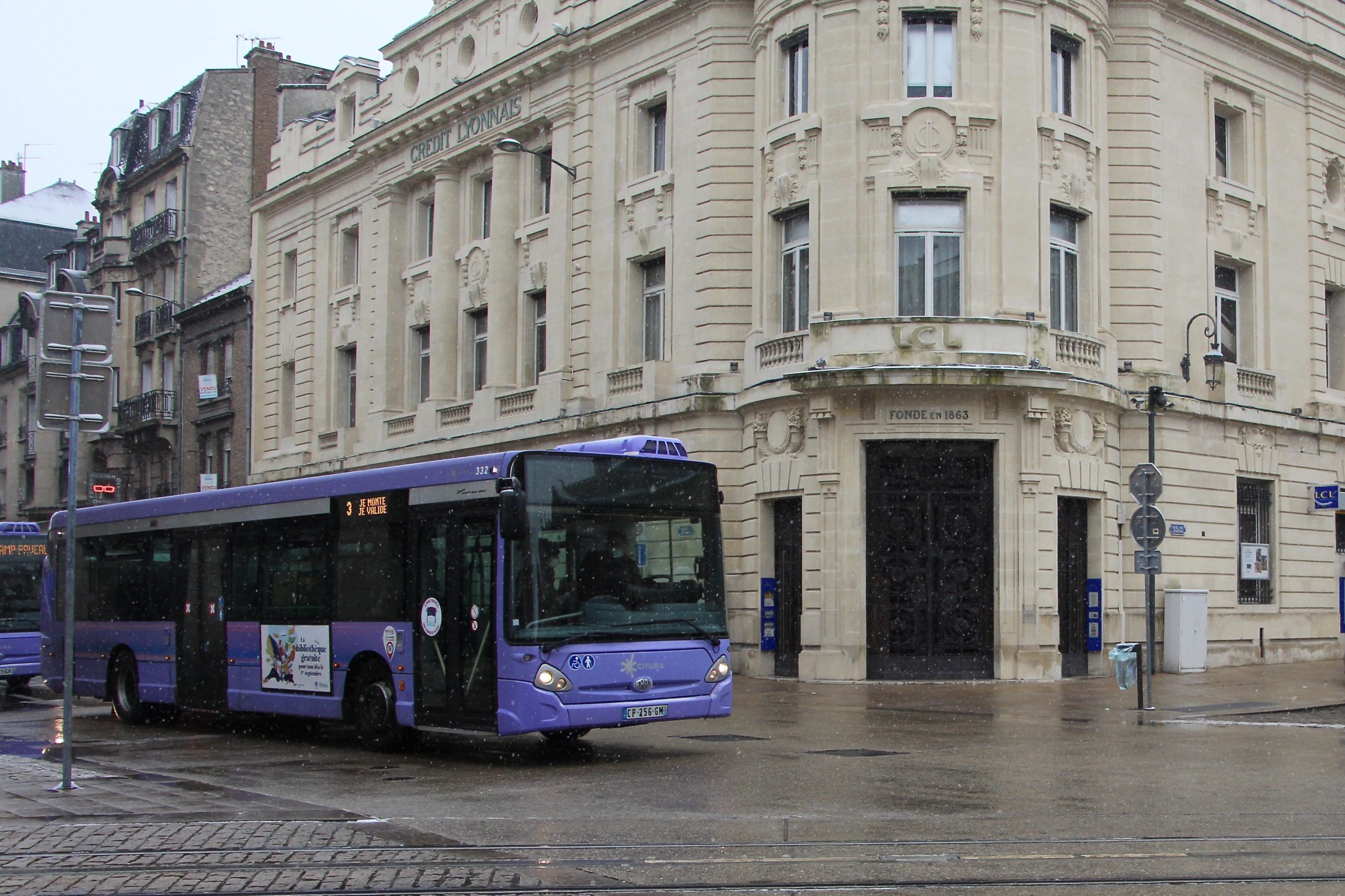 A purple CITURA bus on a street corner in Reims, France.