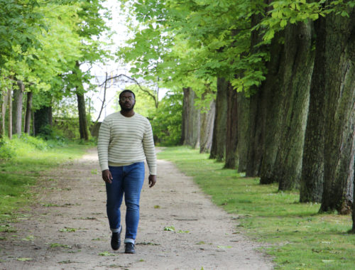 Jalen walks on a pathway lined by trees in the Parc du Champagne in Reims, France.