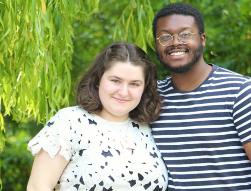 Maria and Jalen smile together in front of a willow tree in Reims, France.