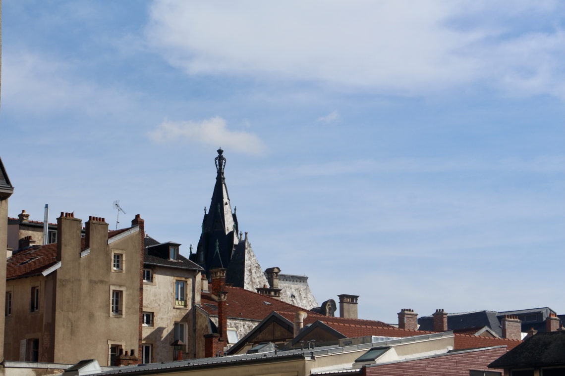 A view of the roofs of Nancy, France with a blue sky in the background.