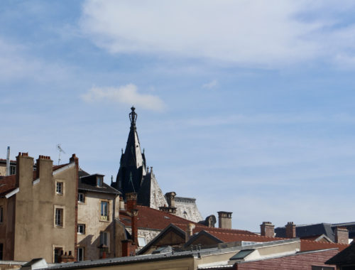 A view of the roofs of Nancy, France with a blue sky in the background.