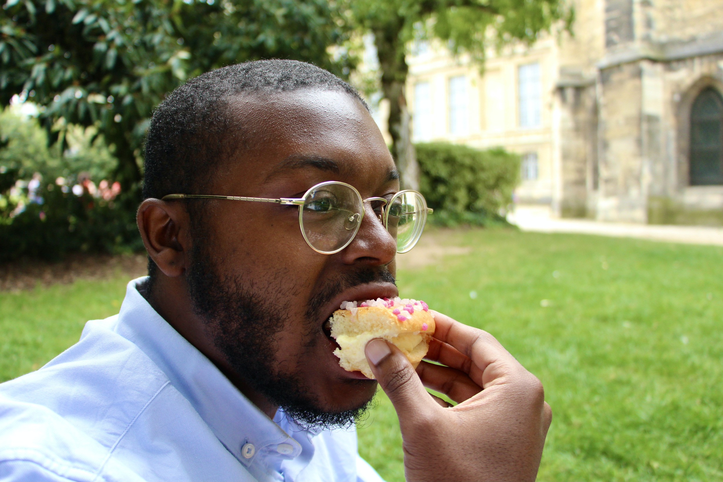 Jalen eating a slice of tropézienne in the gardens of the Cathédrale Notre-Dame de Reims.