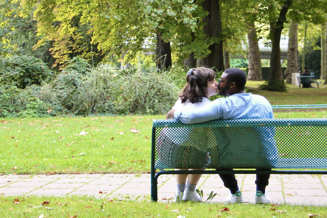 Maria and Jalen kiss on a park bench in Reims, France.