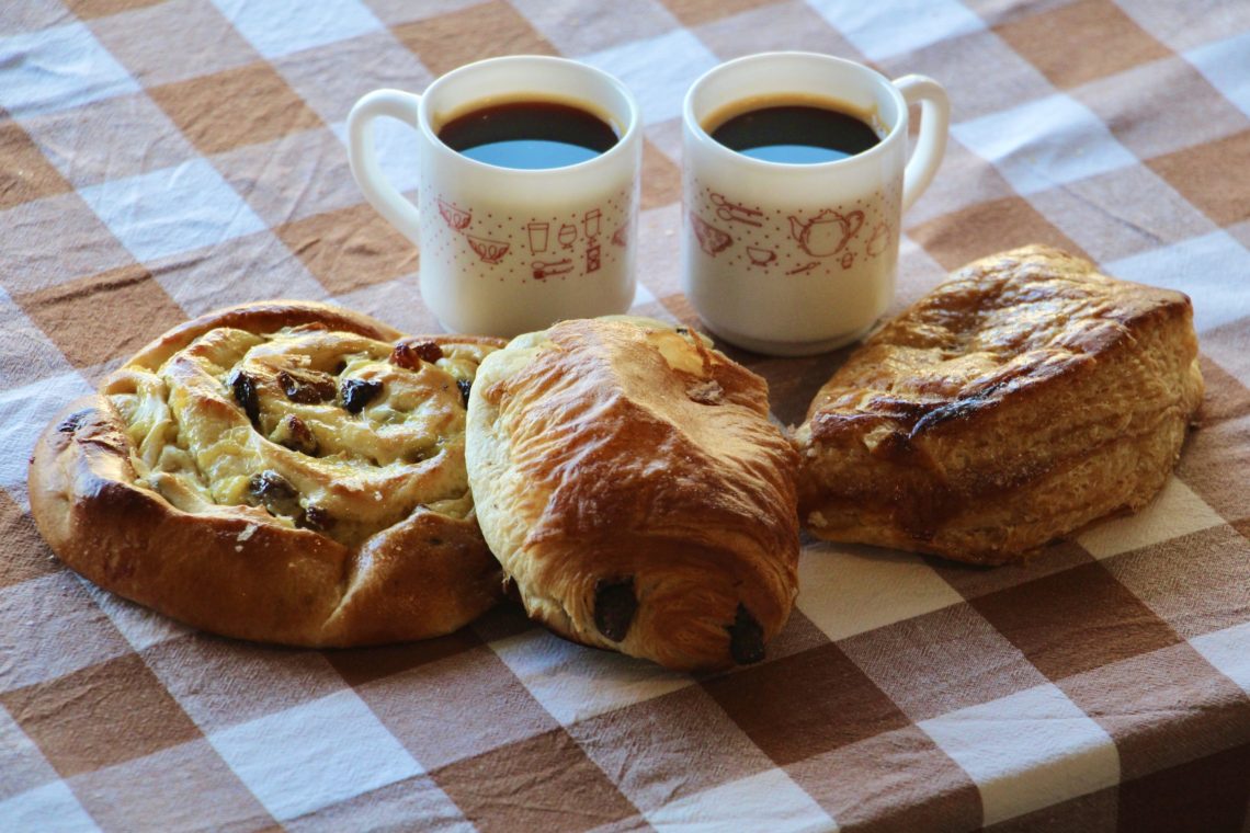 Two demitasse cups, a pain aux raisins, a pain au chocolat, and a chausson aux pommes.