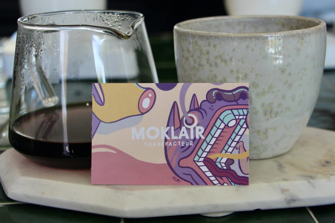 A Moklair business card propped up by a serving of coffee.