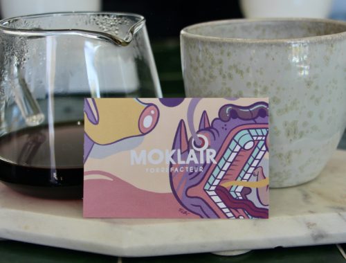 A Moklair business card propped up by a serving of coffee.
