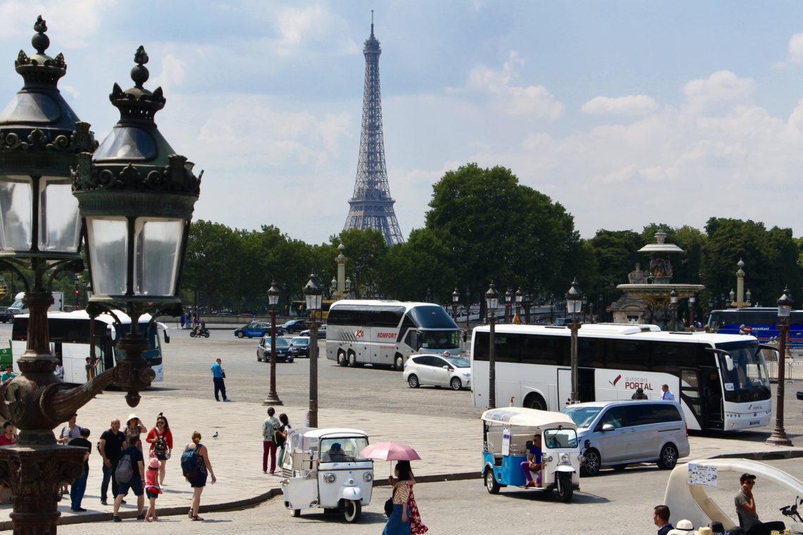 A view of the Eiffel Tower with tourists and vehicles in the streets of Paris, France.