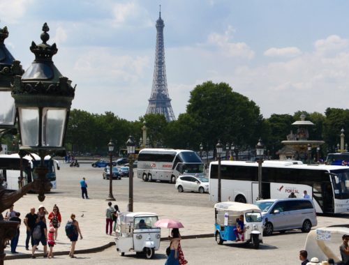 A view of the Eiffel Tower with tourists and vehicles in the streets of Paris, France.
