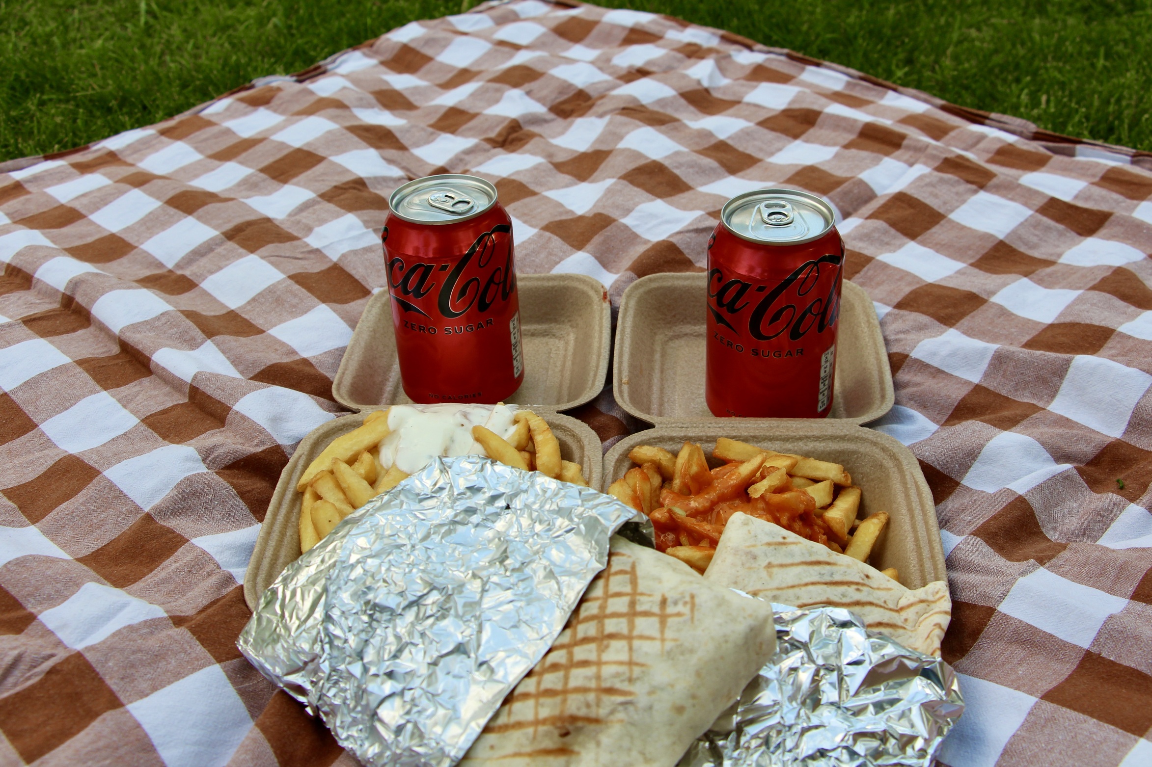 Two French tacos with French fries and two cans of Coke Zero.