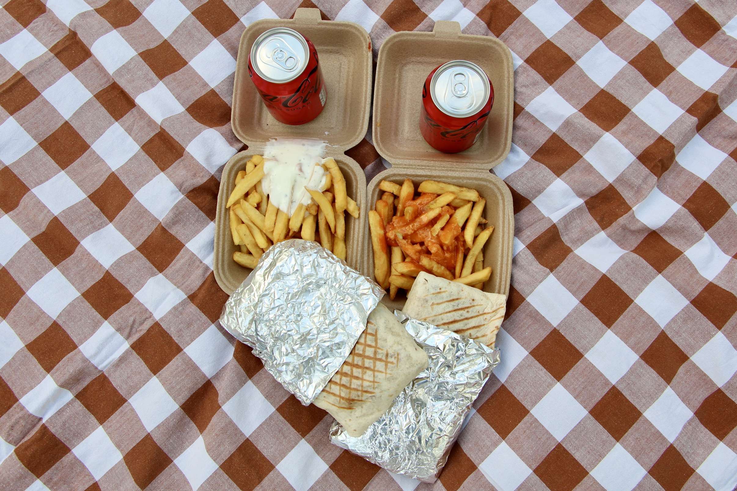 Two French tacos with French fries and two cans of Coke Zero.