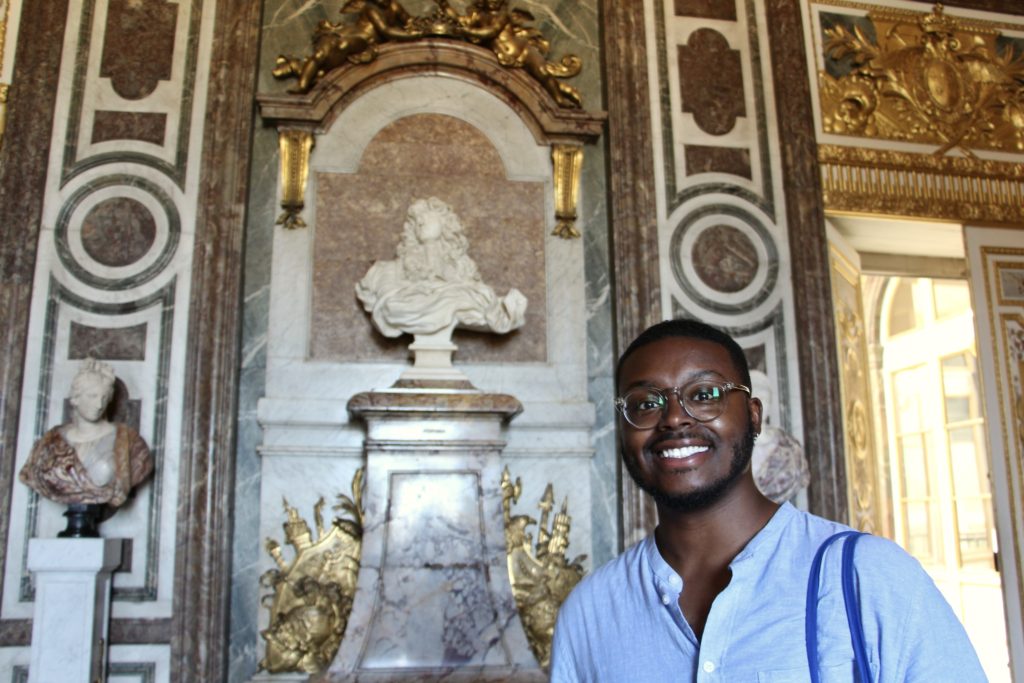 Jalen smiles with Bernini's bust of Louis XIV in the Château de Versailles.