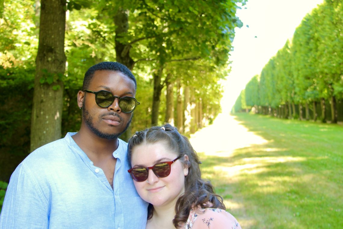 Jalen and Maria pose among the trees on the grounds of the Palace of Versailles.