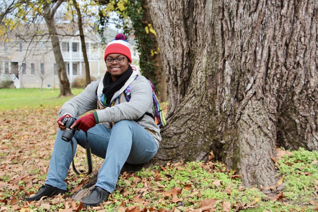 Jalen leaning against a tree trunk in the fall in Fredericksburg, Virginia.