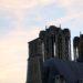 The towers of the Cathédrale Notre-Dame de Reims against a soft orange and blue sky.