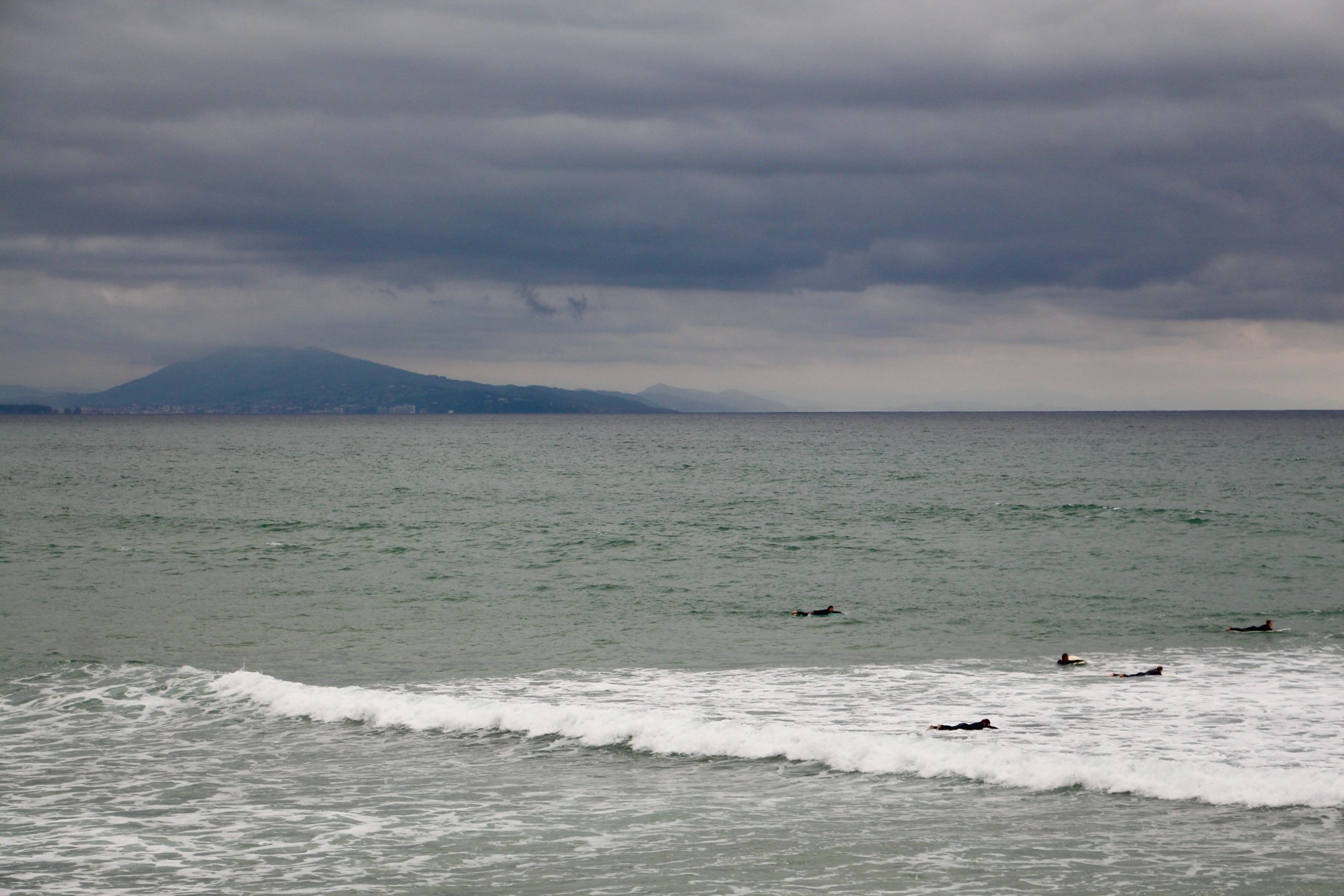 Five surfers in the ocean in Biarritz, France.