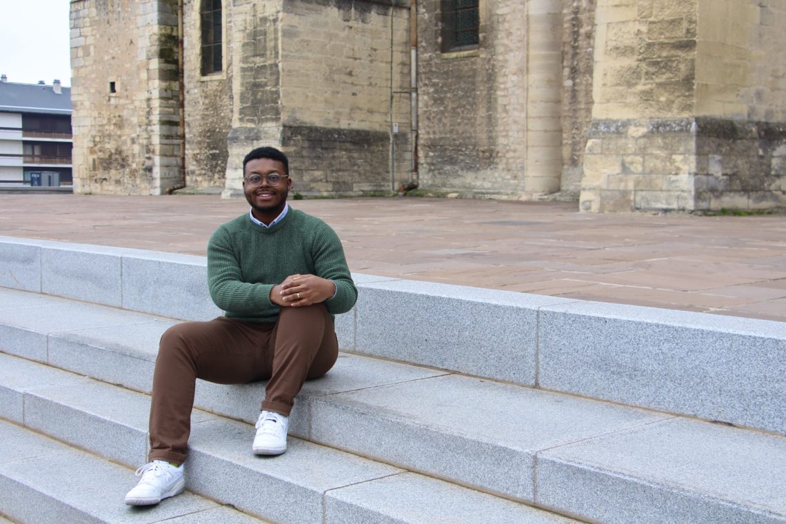 Jalen sitting on the steps of the Basilique Saint-Remi in Reims, France.