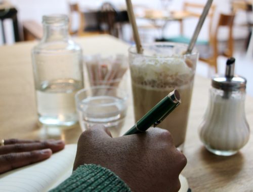 Jalen writing in a notebook at l'Occasion Café in Reims, France.