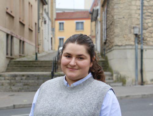 Maria smiles in front of the Rue des Martyrs in Reims, France.