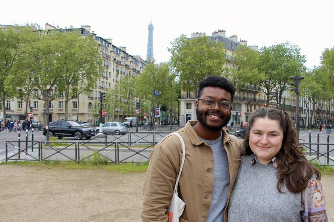 Jalen and Maria pose in front of Parisian buildings and the Eiffel Tower.