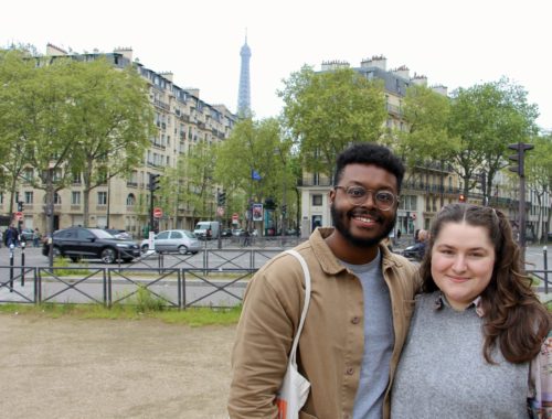 Jalen and Maria pose in front of Parisian buildings and the Eiffel Tower.